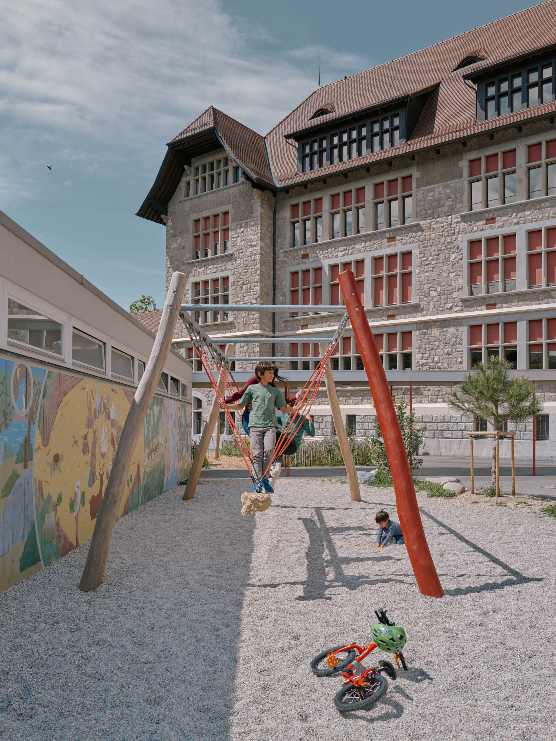 Enfants sur balançoires et fresque murale — préau Collège de la Veveyse photo ©Nicolas Delaroche | Forster Paysages